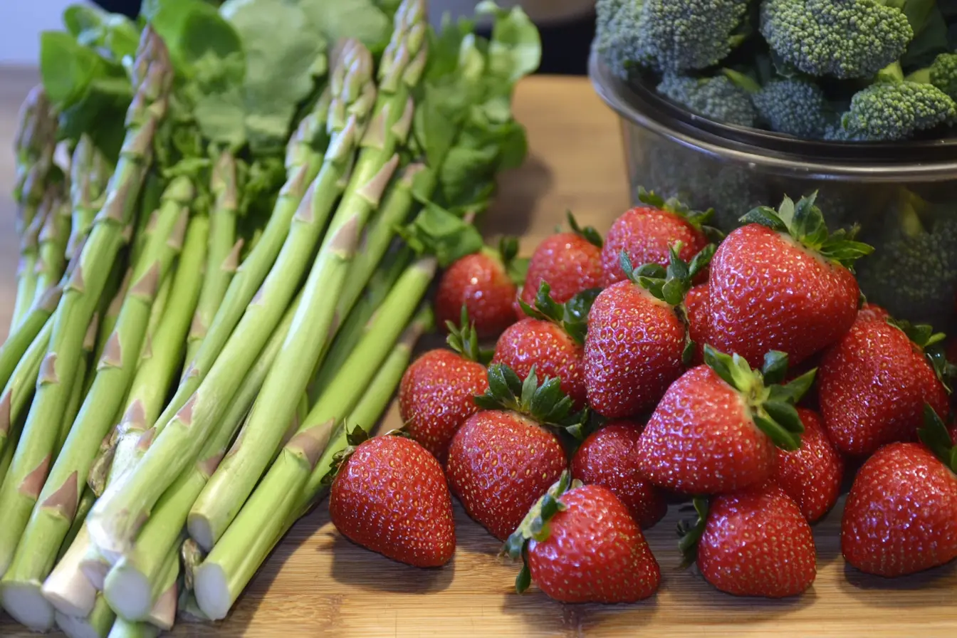 Fresh spring produce including strawberries, asparagus, and greens.